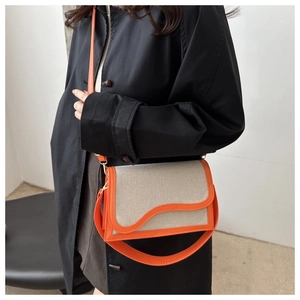 Detail of canvas shoulder bag with orange wave flap and contrast stitching