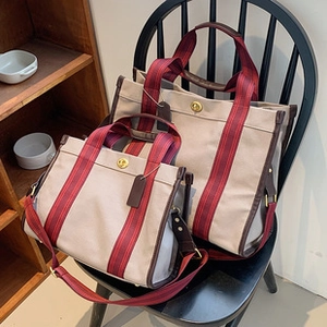 Detail von Vintage-Canvas-Tote-Taschen mit Lederbesatz und Metall-Drehverschluss auf Stuhl