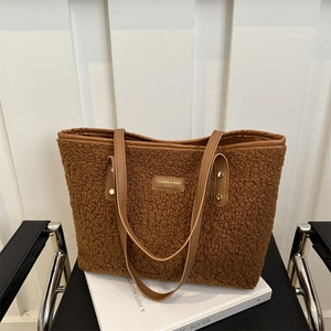 Brown fleece tote bag with leather straps and gold metal logo on white background