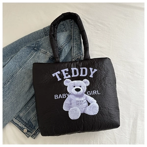 Detail of black quilted down tote bag with a cute purple teddy bear print and text
