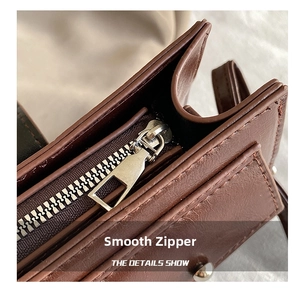 Détail d'une fermeture éclair argentée sur un sac bandoulière vintage en cuir brun