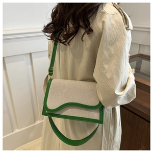 Detail of canvas shoulder bag with green wavy leather trim shown on a model