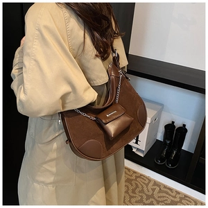 Detail of dark brown leather bucket bag with metallic chain and mini pouch accessory