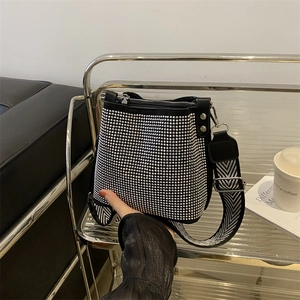 Chic black bucket bag with silver rhinestones and geometric strap on a display rack