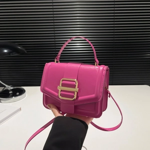 Sac à main magenta avec boucle dorée et bandoulière dans un décor de bureau moderne