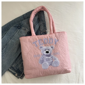 Detailed close-up of a pink quilted puffer tote bag featuring a cute teddy bear print