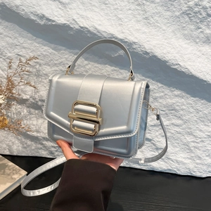Sac à main gris argenté en similicuir avec boucle dorée tenu par un mannequin élégant
