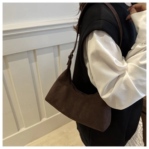 Dettaglio di una borsa hobo in pelle scamosciata marrone scuro indossata da una modella