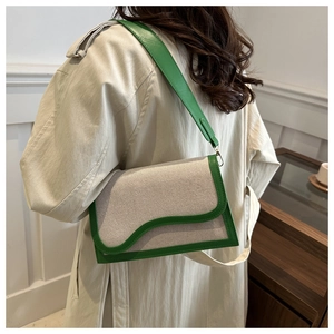 Detail of green leather and beige canvas shoulder bag with wavy flap on model