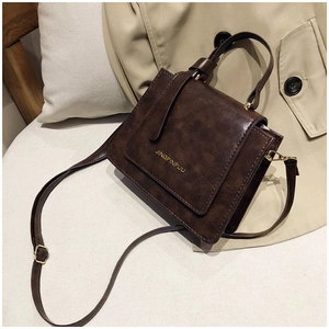 Détail d'un sac bandoulière rétro marron avec texture litchi et logo de marque doré