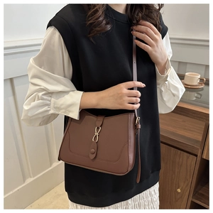 Dettaglio di una borsa hobo a mezzaluna in pelle marrone con fibbia dorata su modella