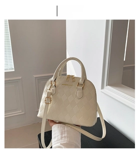Detailed view of white shell bag with quilted leather texture and gold hardware