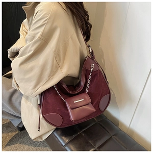 Detail of burgundy suede hobo bag with leather patchwork and mini bag charm chain