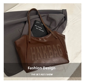 Detailed view of the brown leather tote bag featuring HNK BAG embossed lettering texture