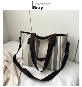 Top view of striped canvas tote bag in grey and white with brown woven handles
