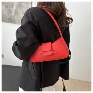 Detail of red bow-knot baguette bag worn by model showing minimalist PU leather texture