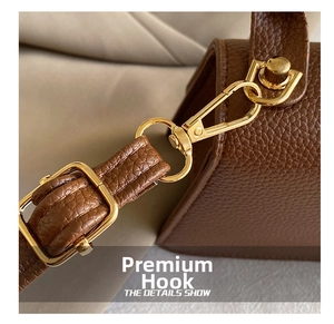 Close-up of premium light gold metal hooks and pebble grain leather strap on a brown bag