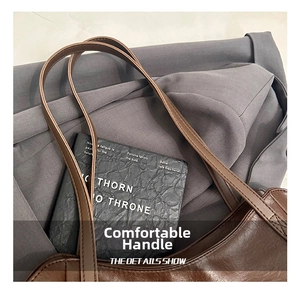 Detail of dark brown leather tote bag showing handle stitching and premium texture