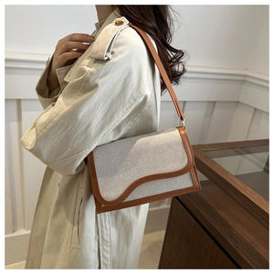 Detail view of canvas patchwork crossbody bag with brown leather trim and wavy flap design