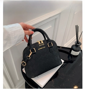 Detail of black shell bag featuring textured rhombic pattern and gold hardware accents
