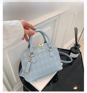Detail of light blue shell bag with diamond quilt texture and gold zipper hardware