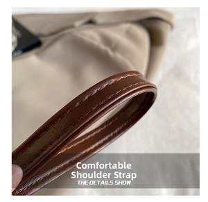 Gros plan sur la bandoulière en similicuir marron avec coutures renforcées du sac beige