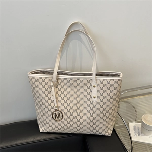 Large beige tote bag with grey M-letter pattern and metal logo charm for women