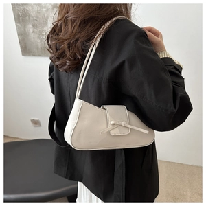 Detail of cream white leather baguette bag with a delicate bow on the side view
