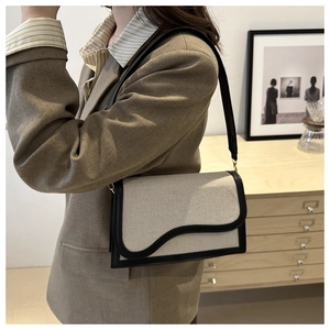 Detail of minimalist canvas crossbody bag with black leather trim shown on shoulder