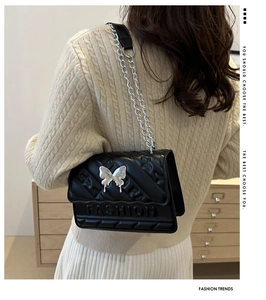 Gros plan du sac bandoulière noir avec boucle papillon et logo en relief