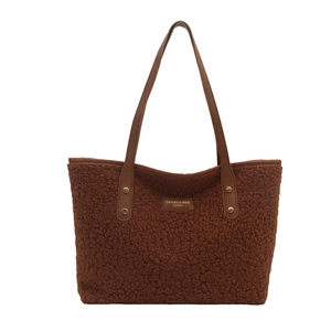 Brown fuzzy teddy tote bag with faux leather straps and gold rivets on white background