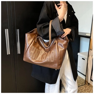 Detail of the HNK BAG logo embossed on dark brown oily leather of this tote bag