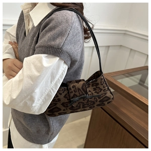 Detail of leopard print baguette bag with a black bow and slender shoulder strap