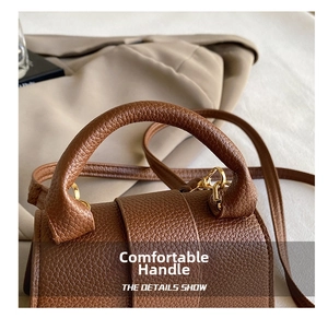Detailed close-up of brown litchi grain leather handle with gold hardware for handbags