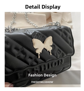 Detail of black quilted leather handbag with gold butterfly buckle and chain strap