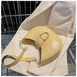 Detail of beige faux crocodile texture bag with golden D buckle and pearl strap decor
