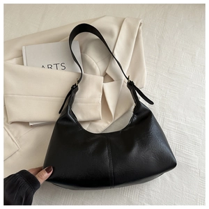 Detail of black crescent faux suede shoulder bag with adjustable strap and vertical seam