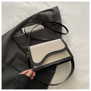 Detail of minimalist beige woven shoulder bag with wavy flap and black leather piping