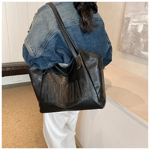 Detail of black large capacity leather tote bag with HINKBAG embossed logo on model
