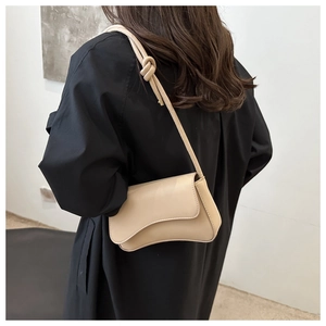 Vue détaillée du sac beige en croissant avec bandoulière nouée et rabat magnétique