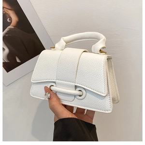 Detail of white lychee leather handbag featuring gold metal eyelets and top handle