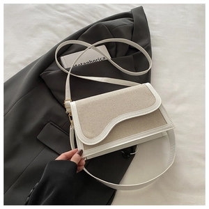 Detail of contrast stitch patchwork handbag with white leather trim and beige canvas fabric