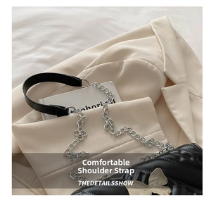 Detail of silver chain strap and butterfly buckle on black quilted crossbody bag