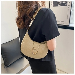 Detail of beige faux crocodile texture shoulder bag with decorative pearls and U-shaped buckle