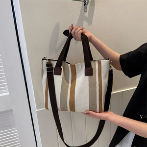 Vertical striped canvas tote bag with brown handles and adjustable crossbody strap