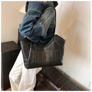Detail shot of the HNKBAG embossed logo on black large capacity faux leather tote bag