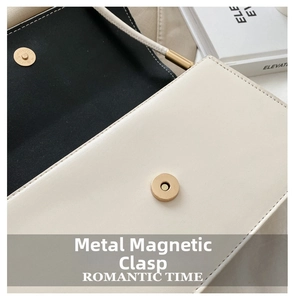 Dettaglio della chiusura magnetica dorata sulla borsa in pelle beige e nera