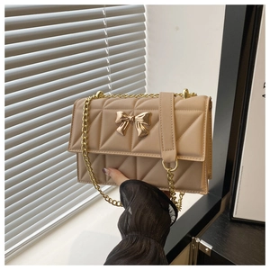 Dettaglio macro della borsa trapuntata beige con chiusura a farfalla dorata e catena