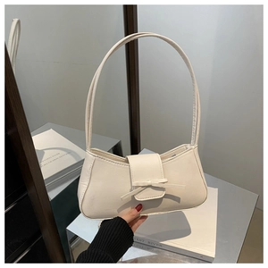 Detailed view of cream bow baguette bag with matte leather and elegant half-moon shape
