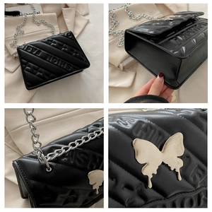 Detail of black quilted shoulder bag featuring fashion embossing and a silver butterfly clasp